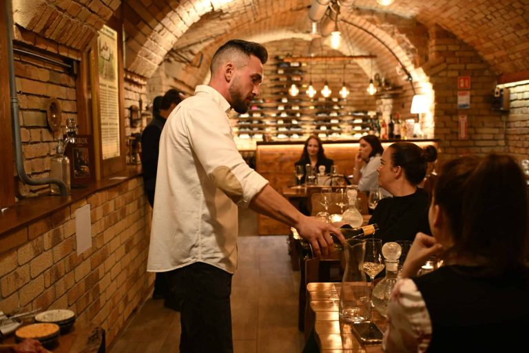 Host pouring wine for guests in the Goldcentral cellar